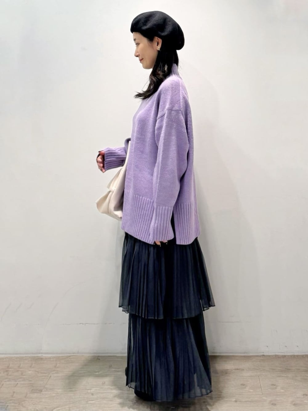 パープル系のニット/セーター、グレー系のスカート、ホワイト系のトートバッグを着用したレディースの秋コーディネートの2枚目の写真