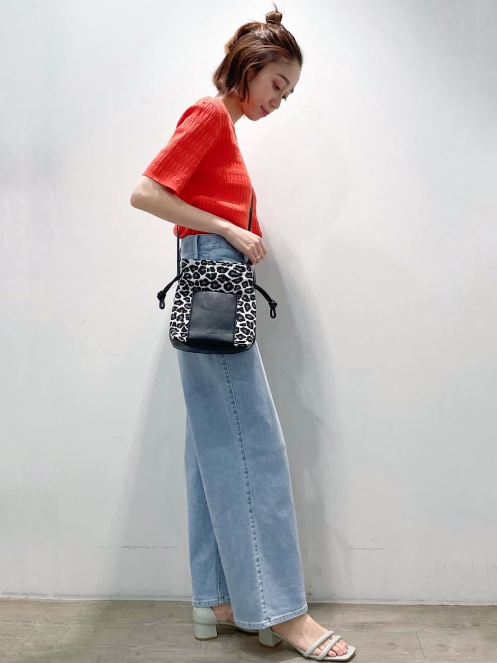 オレンジ系のニット/セーター、ブルー系のデニムパンツ、グリーン系のサンダルを着用したレディースの春コーディネートの3枚目の写真