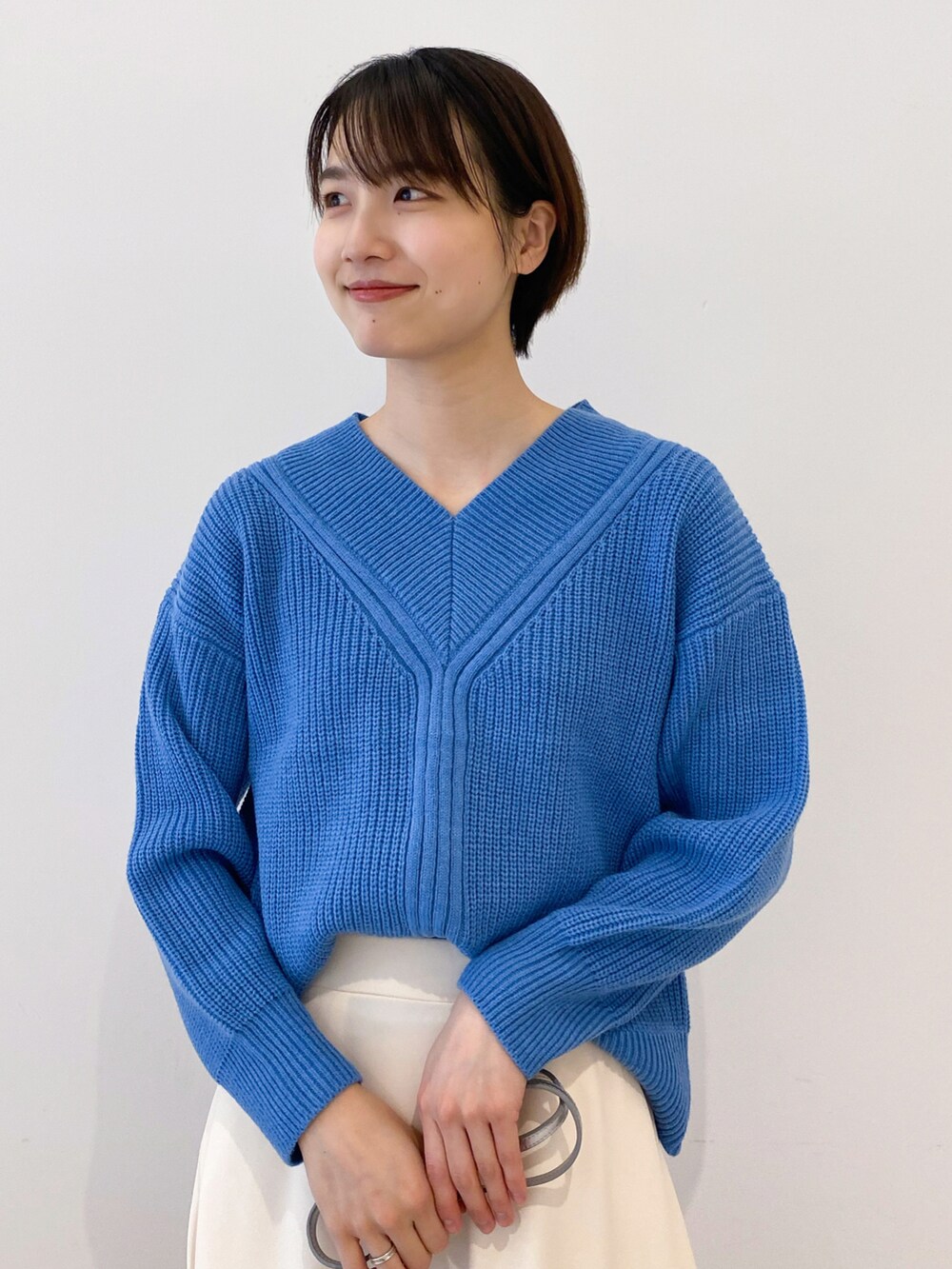 ホワイト系のスカート、シルバー系のショルダーバッグ、ブルー系のニット/セーターを着用したレディースの冬コーディネートの2枚目の写真