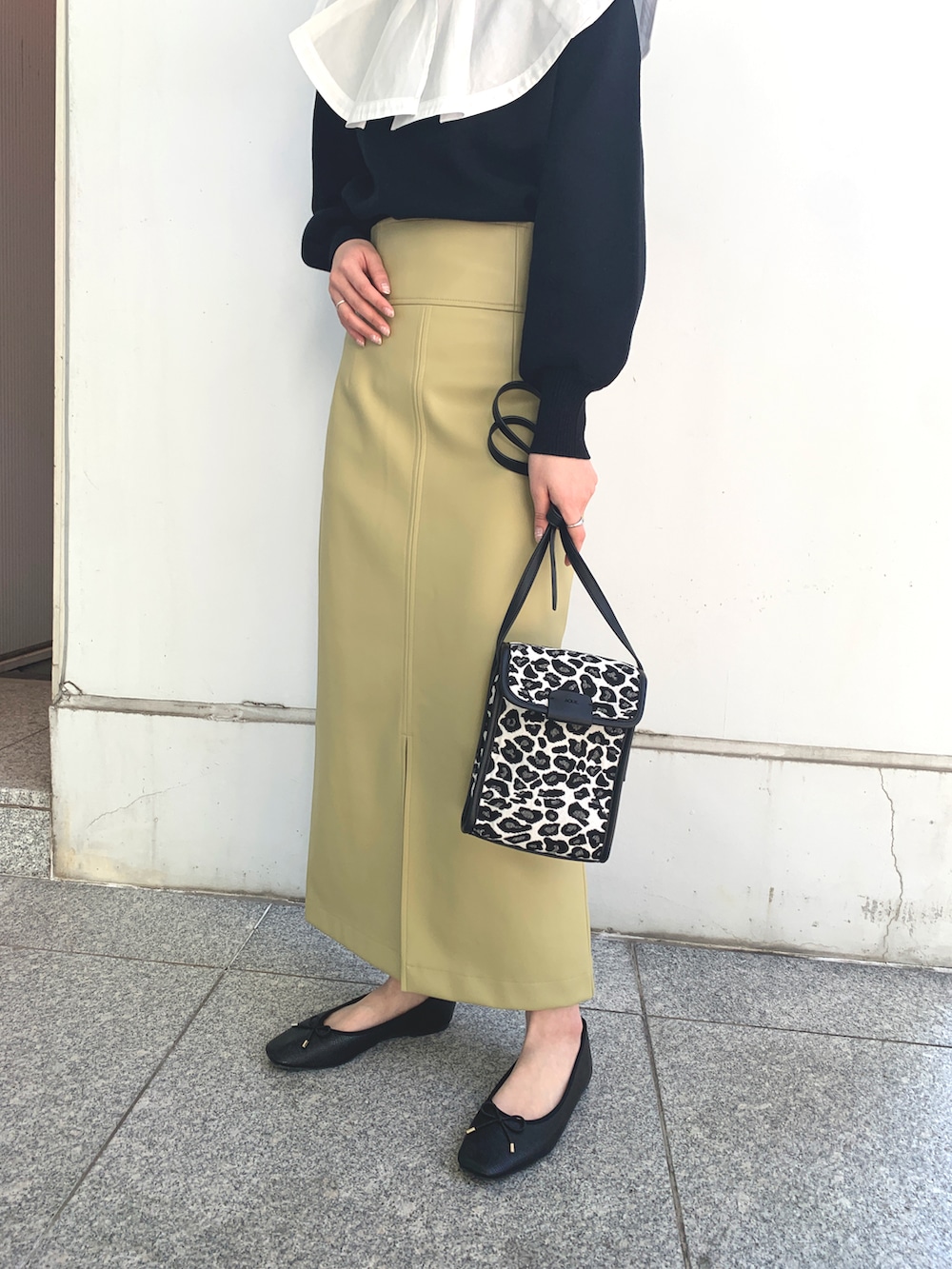 ブラック系のドレスシューズ、イエロー系のスカート、ブラック系のニット/セーターを着用したレディースの春コーディネートの2枚目の写真