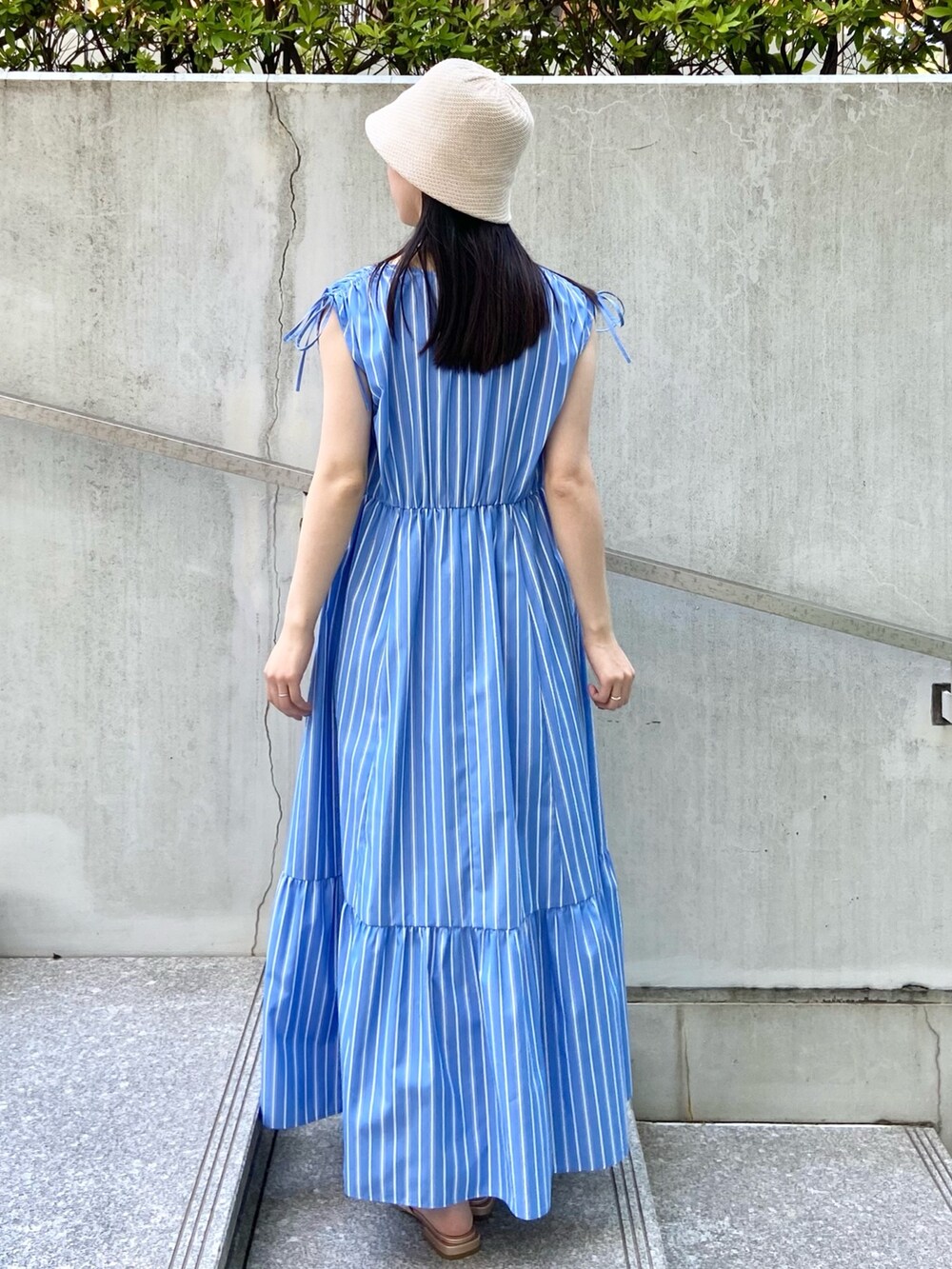 ブルー系のワンピース、ゴールド系のサンダル、ホワイト系のハットを着用したレディースの夏コーディネートの3枚目の写真