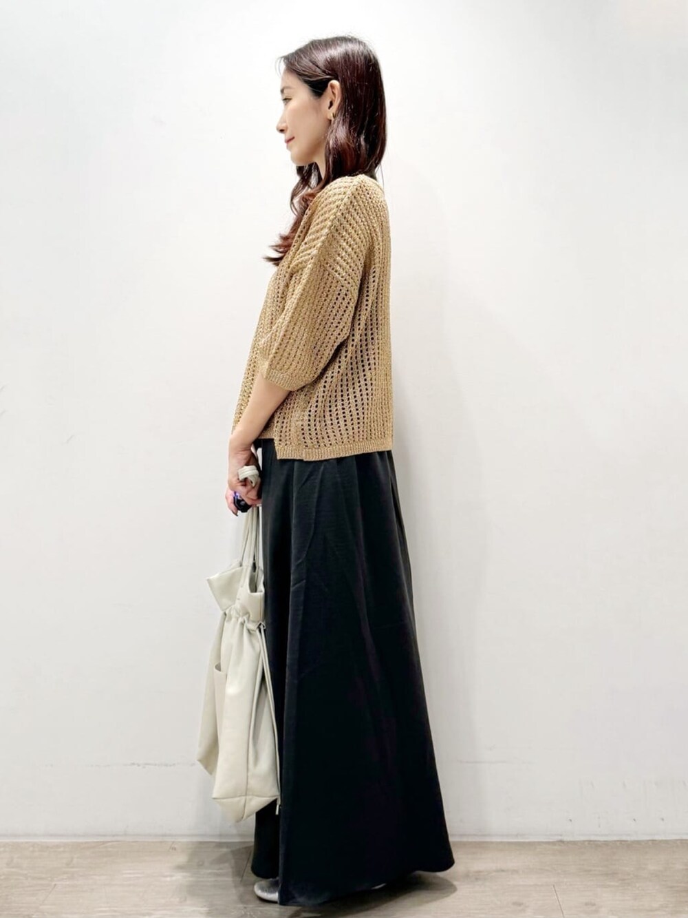 ゴールド系のニット/セーター、グレー系のトートバッグ、グレー系のスカートを着用したレディースの秋コーディネートの4枚目の写真