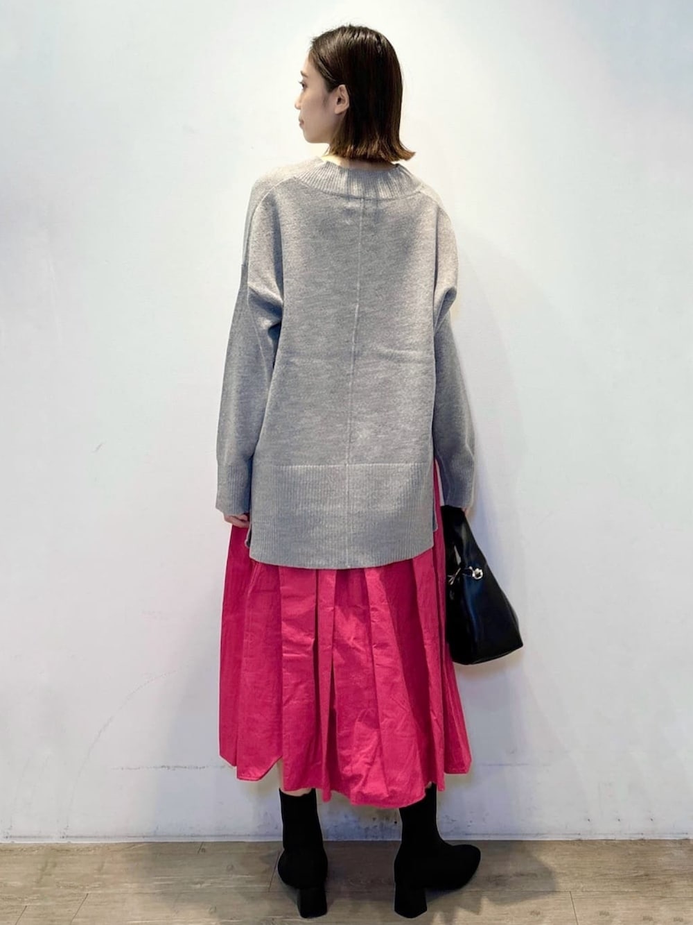 グレー系のニット/セーター、ピンク系のスカート、ブラック系のショルダーバッグを着用したレディースの冬コーディネートの4枚目の写真