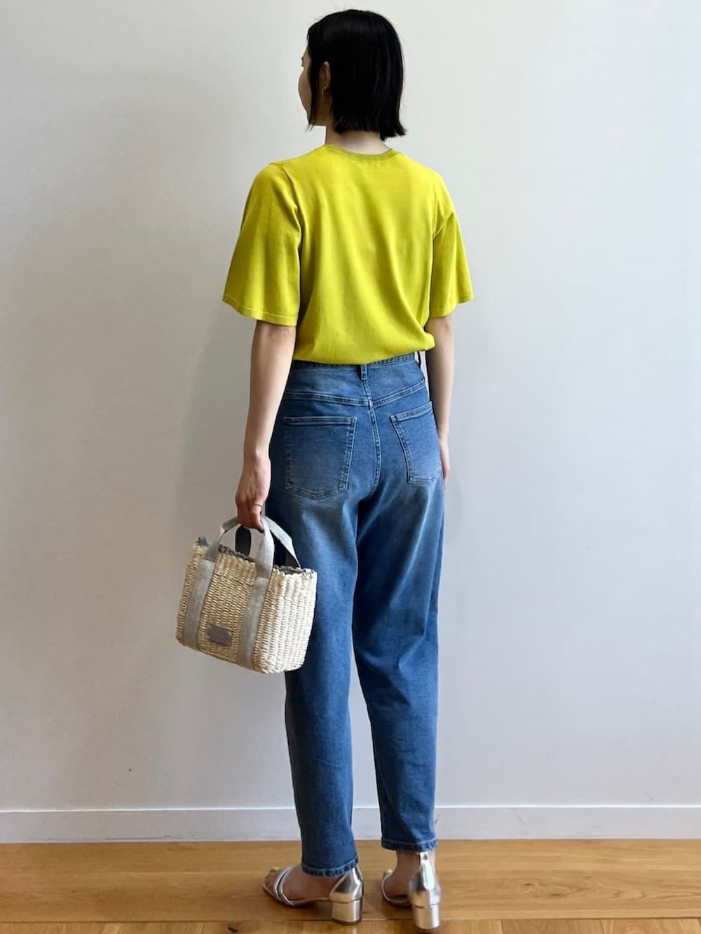 グリーン系のニット/セーター、ブルー系のデニムパンツ、シルバー系のショルダーバッグを着用したレディースの夏コーディネートの4枚目の写真