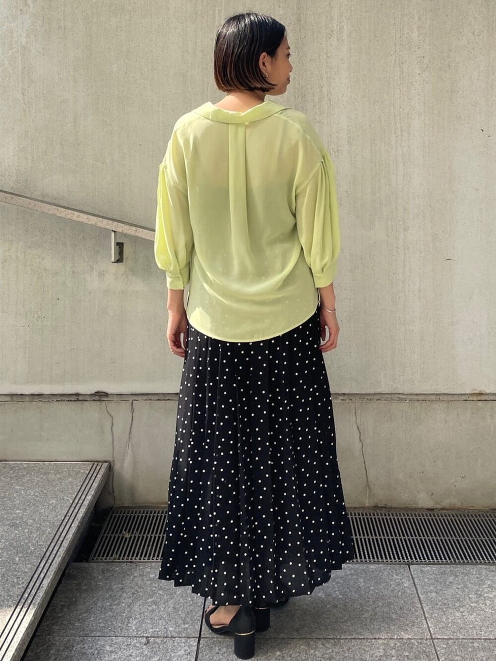 グリーン系のシャツ/ブラウス、ブラック系のスカート、ブラック系のサンダルを着用したレディースの春コーディネートの2枚目の写真