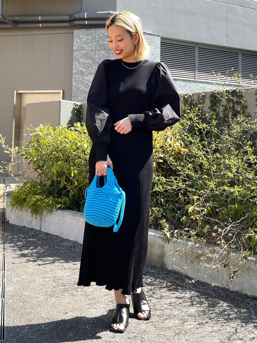 ホワイト系のデニムジャケット、ブルー系のショルダーバッグ、ブラック系のワンピースを着用したレディースの春コーディネートの2枚目の写真