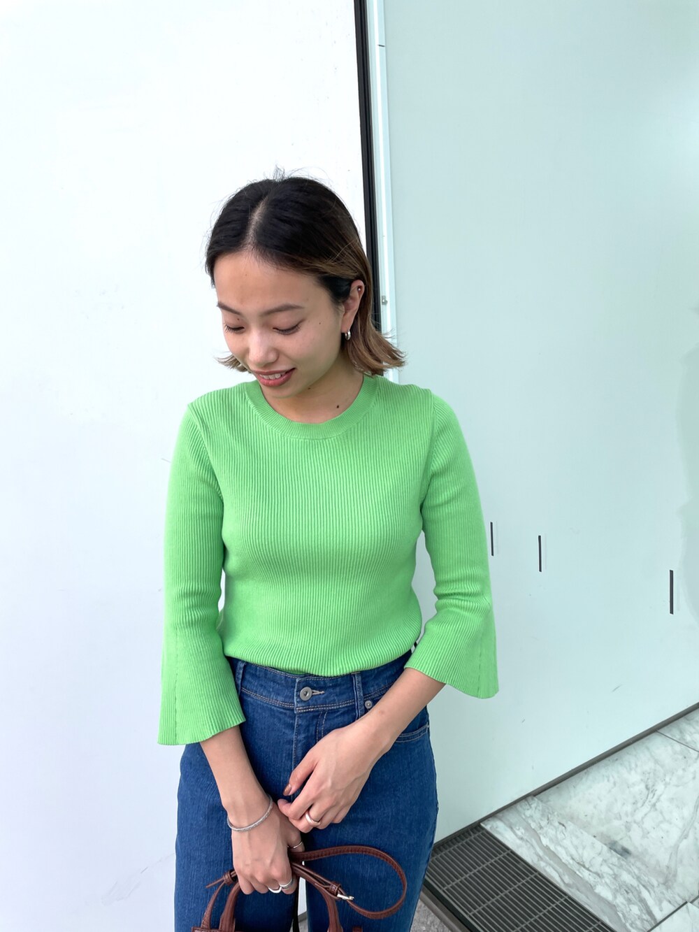 グリーン系のニット/セーター、ブルー系のその他パンツ、ブラウン系のショルダーバッグを着用したレディースの秋コーディネートの3枚目の写真