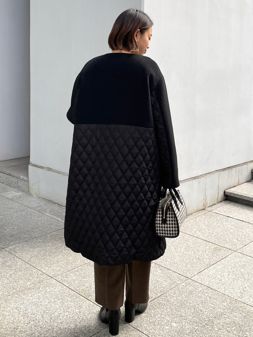 イエロー系のニット/セーター、ブラック系のノーカラーコート、ブラウン系のその他パンツを着用したレディースの冬コーディネートの3枚目の写真