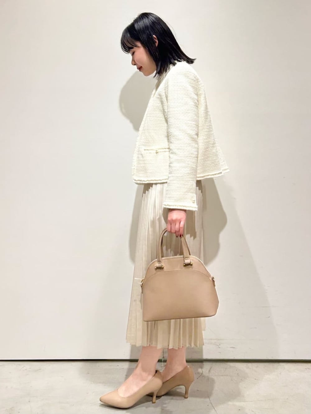 ホワイト系のノーカラージャケット、ベージュ系のワンピース、ベージュ系のトートバッグを着用したレディースの冬コーディネートの2枚目の写真