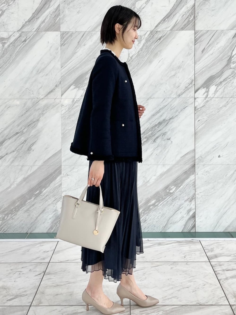 ブルー系のスカート、ホワイト系のシャツ/ブラウス、ブルー系のノーカラージャケットを着用したレディースの冬コーディネートの2枚目の写真