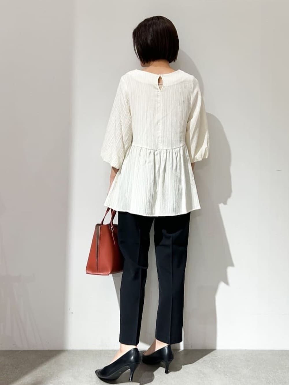 ホワイト系のシャツ/ブラウス、ブラック系のパンプス、レッド系のトートバッグを着用したレディースの夏コーディネートの4枚目の写真