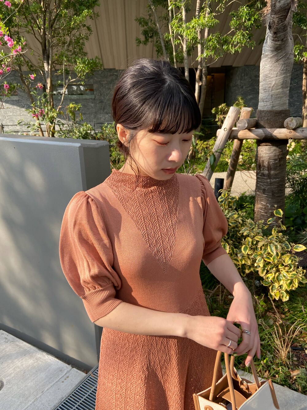 オレンジ系のワンピース、ベージュ系のドレスシューズ、イエロー系のトートバッグを着用したレディースの春コーディネートの2枚目の写真