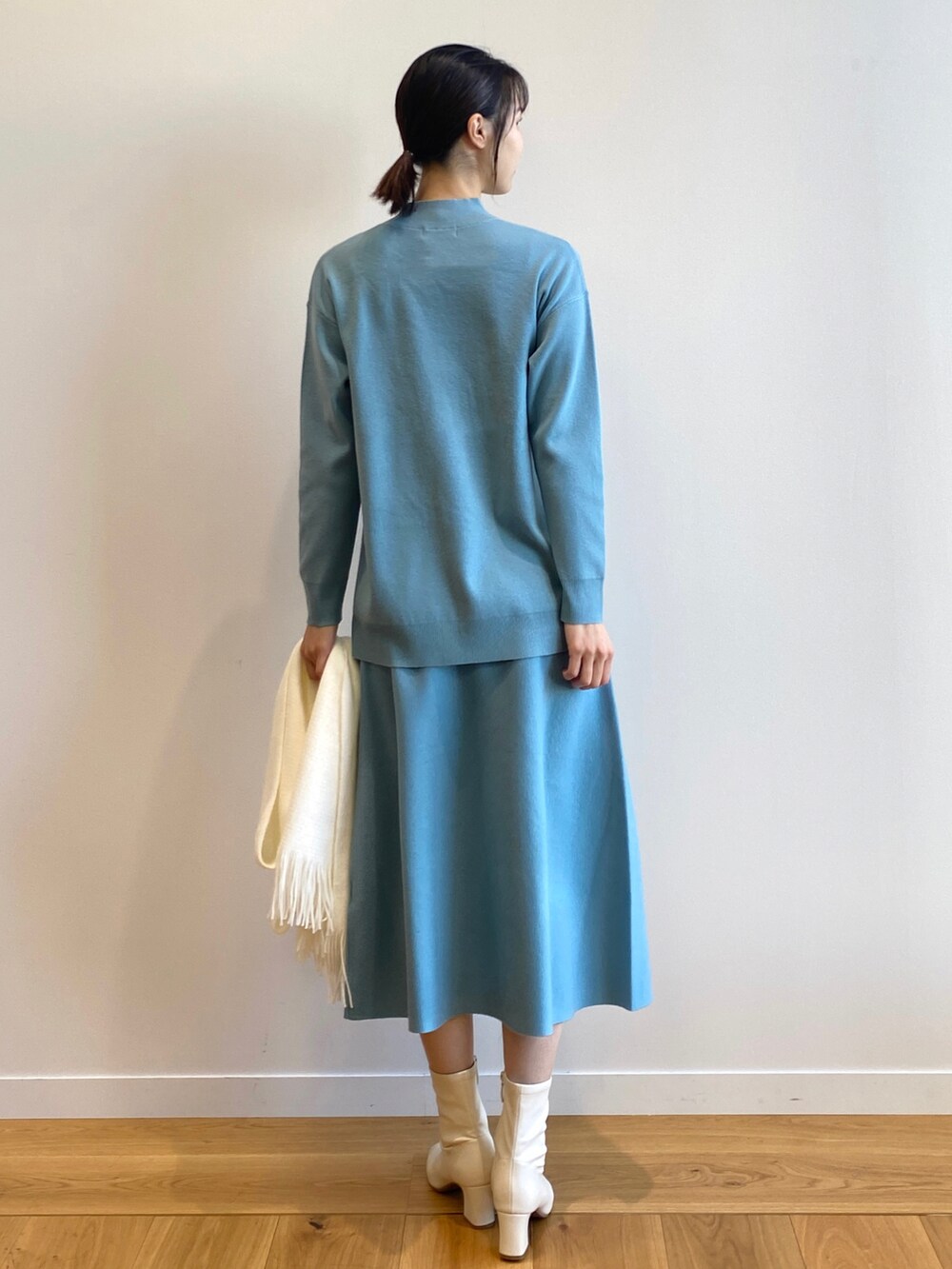 ブルー系のニット/セーター、ブルー系のスカート、ホワイト系のブーツを着用したレディースの冬コーディネートの3枚目の写真