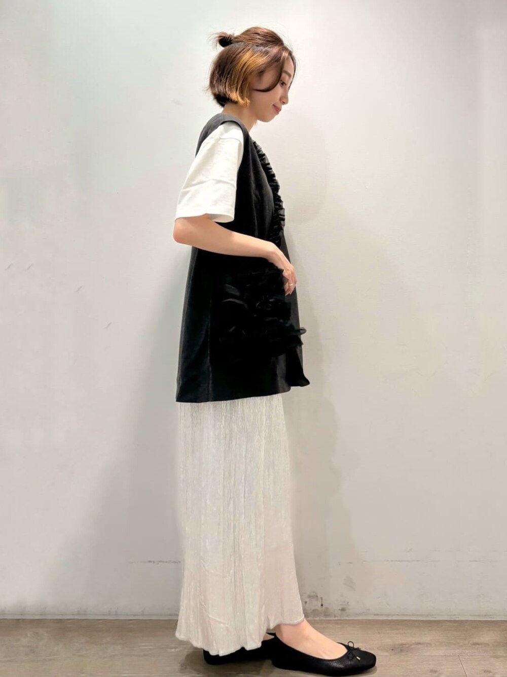 シルバー系のスカート、グレー系のベスト、ホワイト系のTシャツ/カットソーを着用したレディースの夏コーディネートの3枚目の写真