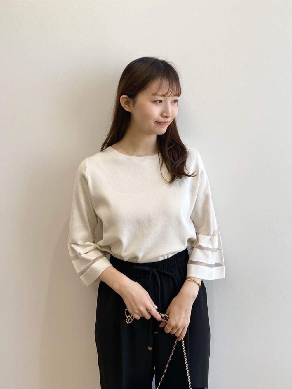 ホワイト系のニット/セーター、ブラック系のその他パンツ、ブラック系のショルダーバッグを着用したレディースの春コーディネートの6枚目の写真