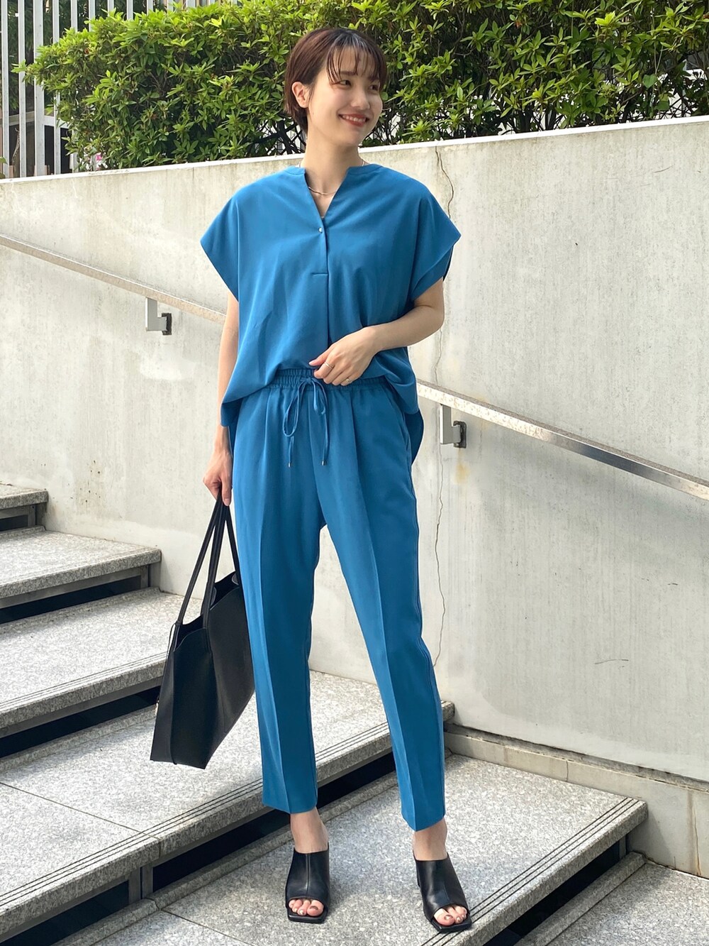 ブルー系のシャツ/ブラウス、ブルー系のその他パンツ、ブラック系のトートバッグを着用したレディースの夏コーディネートの4枚目の写真