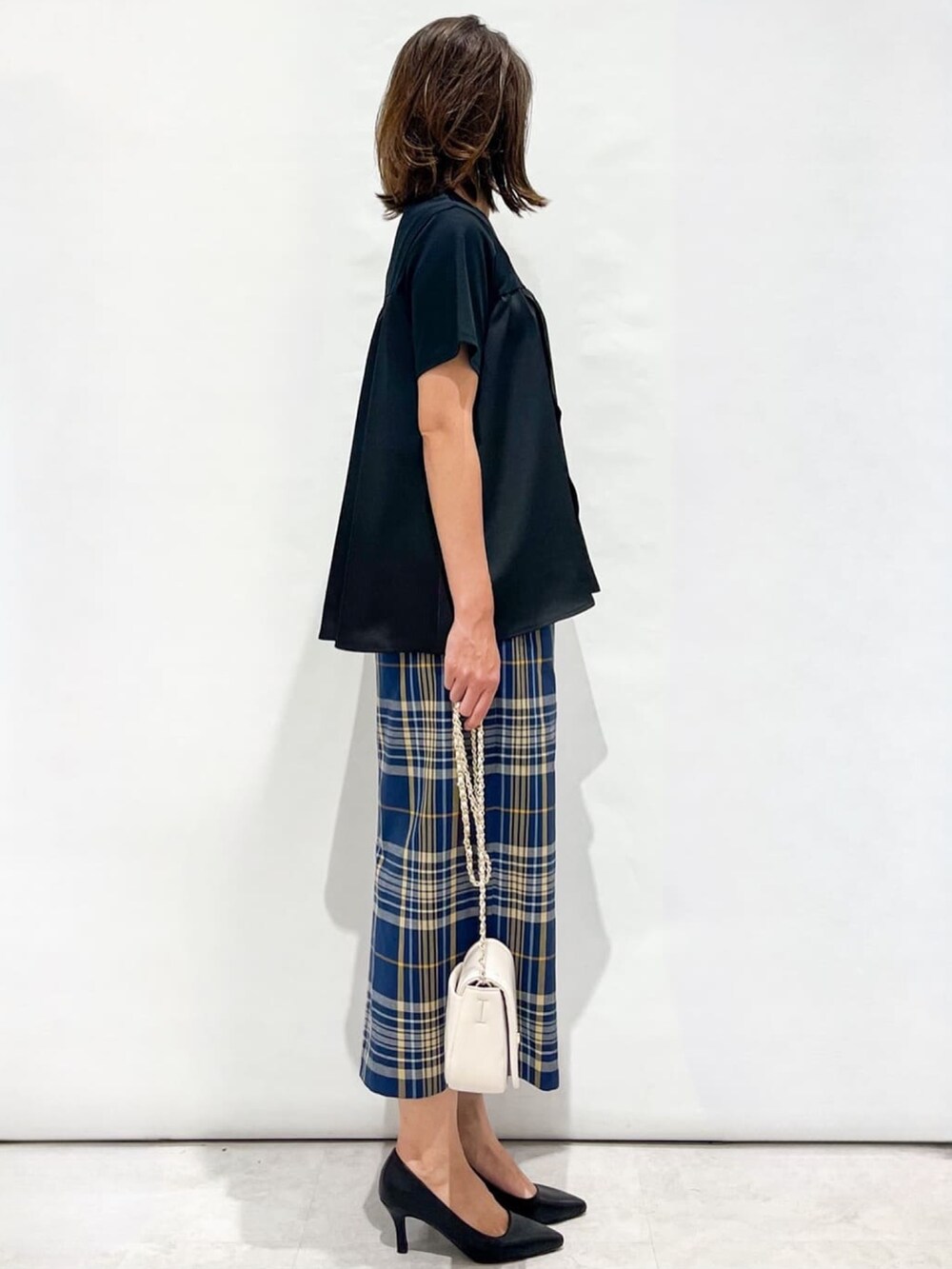 ブルー系のスカート、ブラック系のパンプス、ホワイト系のショルダーバッグを着用したレディースの夏コーディネートの5枚目の写真