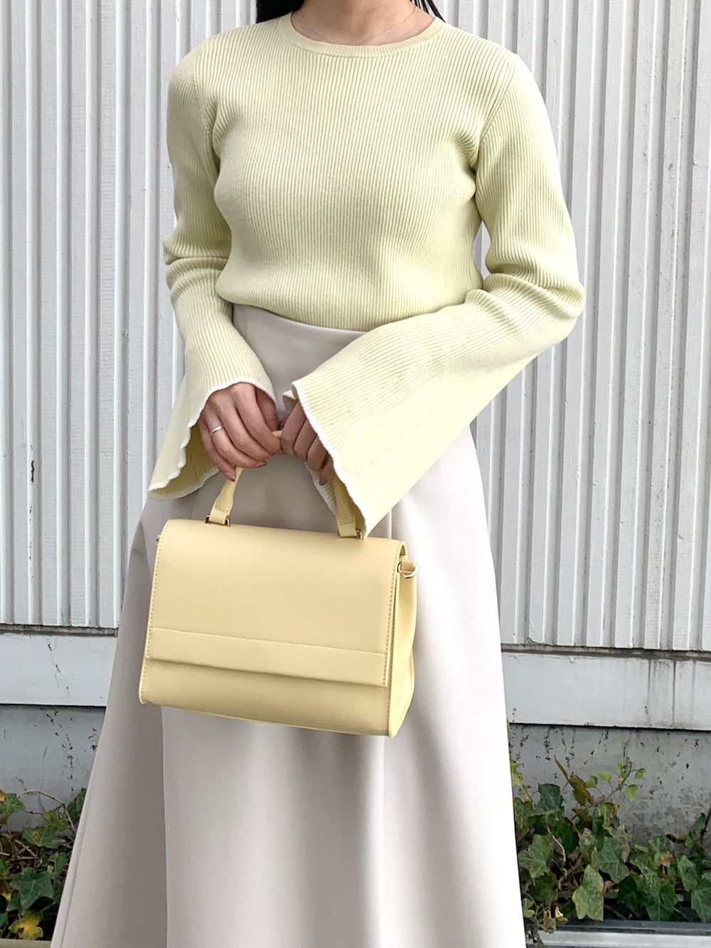 グレー系のブルゾン、イエロー系のニット/セーター、グレー系のスカートを着用したレディースの春コーディネートの4枚目の写真