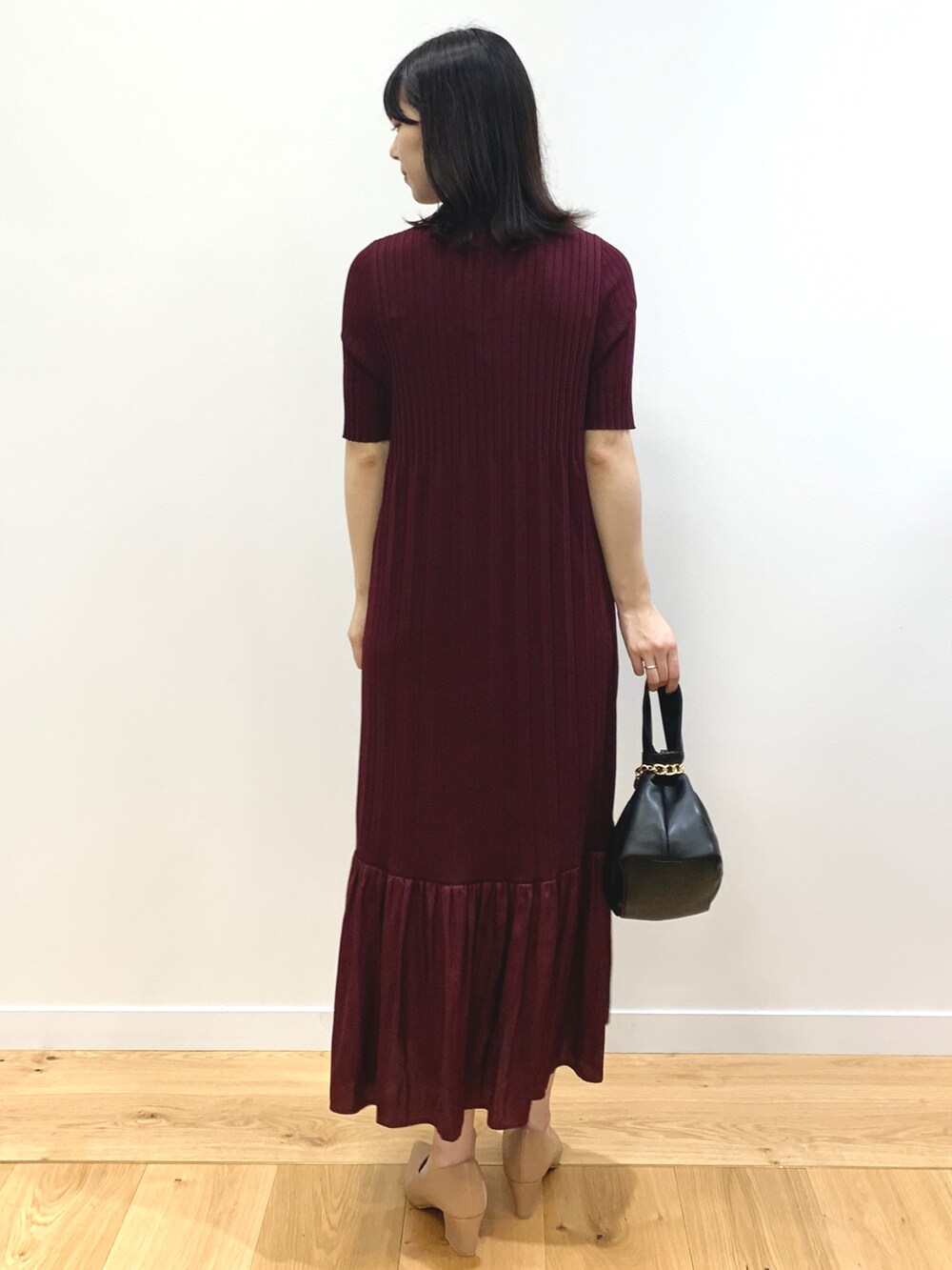 レッド系のワンピース、ブラック系のハンドバッグ、ベージュ系のパンプスを着用したレディースの夏コーディネートの4枚目の写真