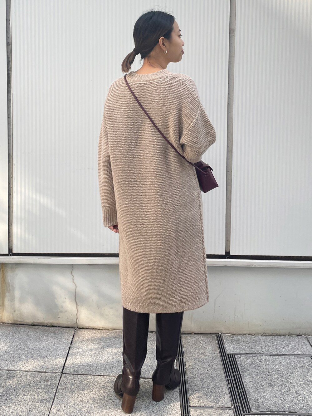 ベージュ系のワンピース、レッド系のショルダーバッグ、ブラウン系のブーツを着用したレディースの冬コーディネートの3枚目の写真