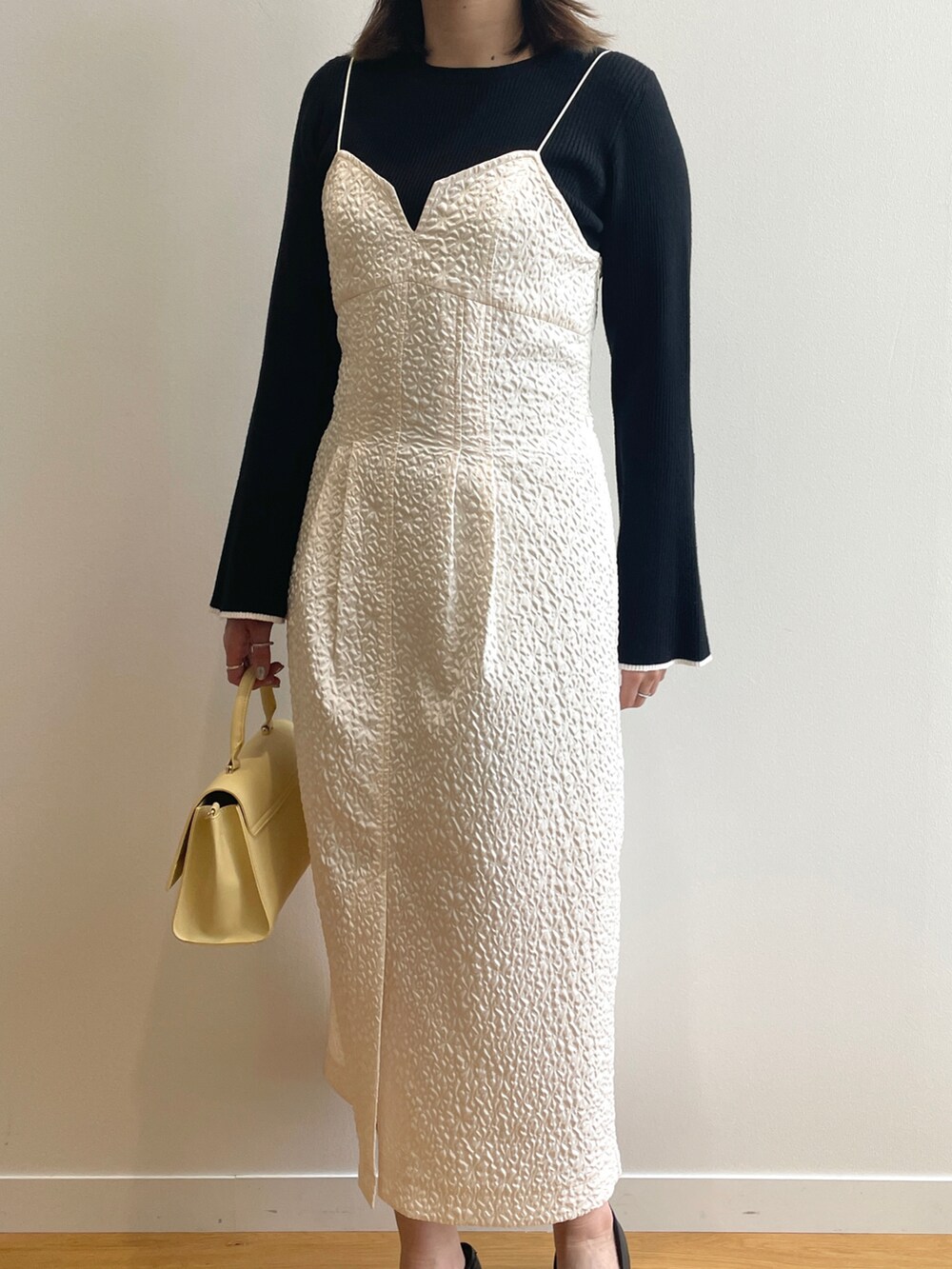 ベージュ系のトレンチコート、ホワイト系のワンピース、イエロー系のショルダーバッグを着用したレディースの春コーディネートの5枚目の写真