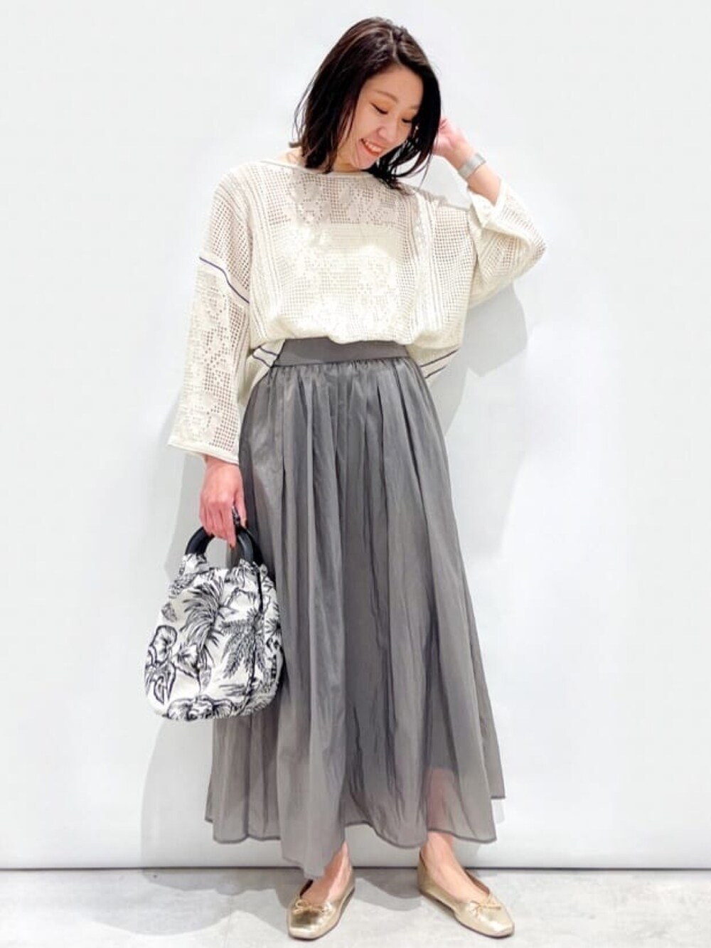 ホワイト系のニット/セーター、グレー系のスカート、ホワイト系のハンドバッグを着用したレディースの春コーディネートの3枚目の写真