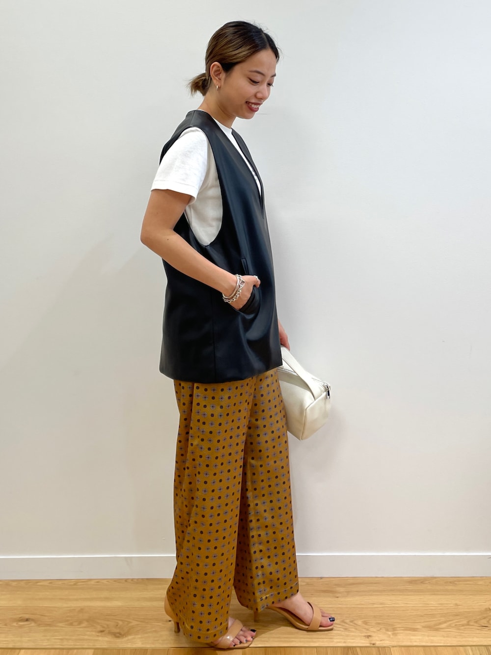 ホワイト系のTシャツ/カットソー、ブラック系のベスト、イエロー系のその他パンツを着用したレディースの夏コーディネートの2枚目の写真