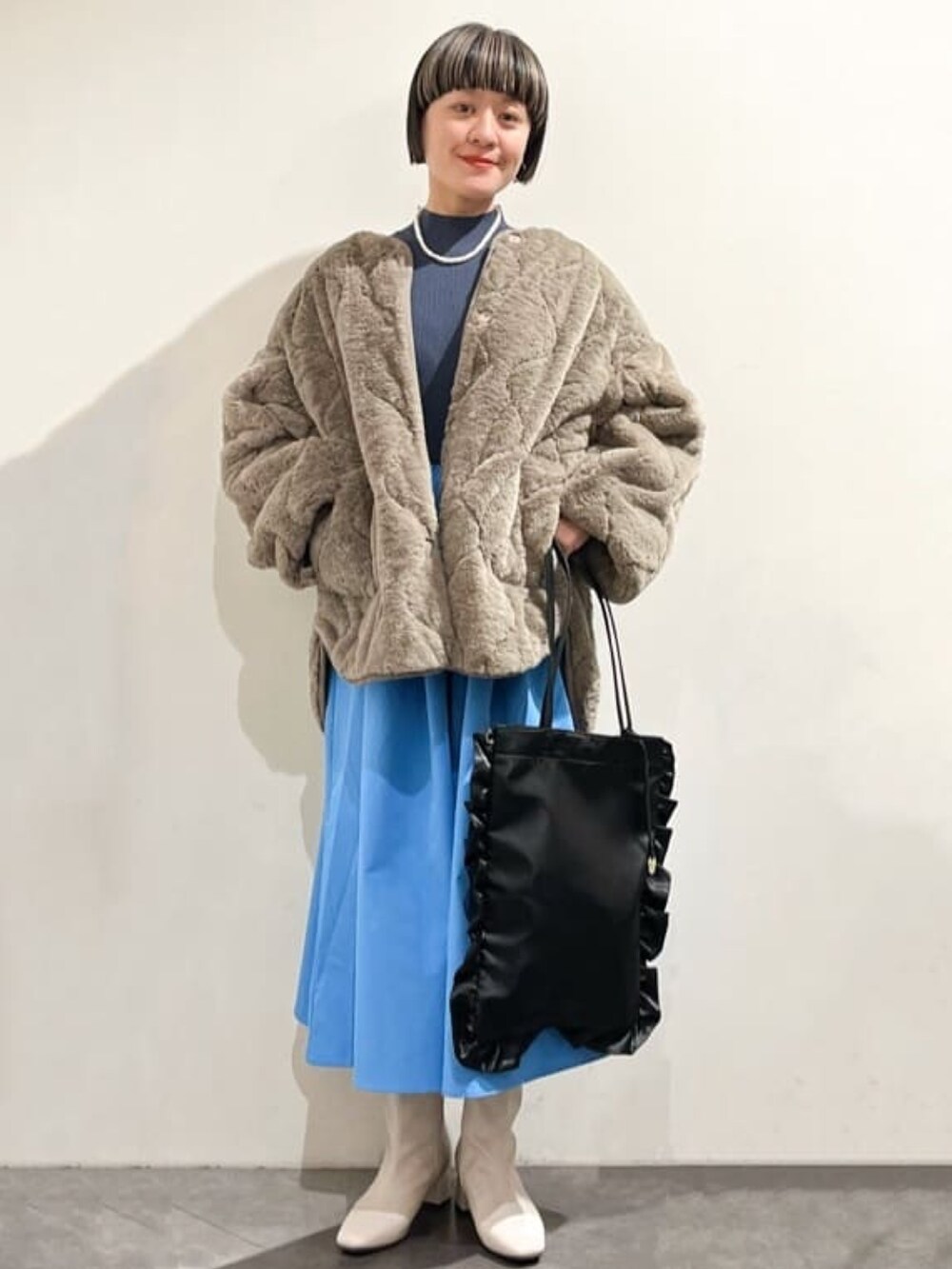 グレー系のワンピース、ベージュ系のノーカラーコート、ブラック系のトートバッグを着用したレディースの冬コーディネートの2枚目の写真