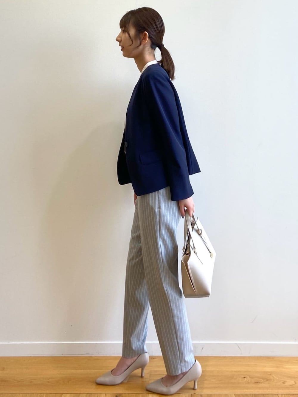 ブルー系のノーカラージャケット、グレー系のその他パンツ、ベージュ系のトートバッグを着用したレディースの春コーディネートの2枚目の写真