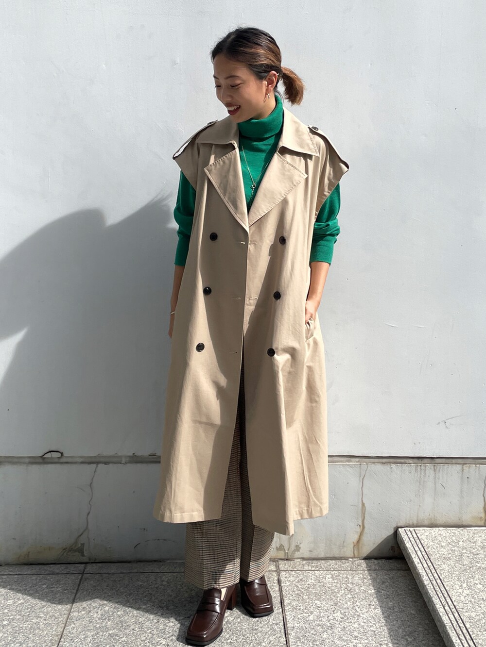 ベージュ系のトレンチコート、グリーン系のニット/セーター、ブラウン系のその他パンツを着用したレディースの秋コーディネートの3枚目の写真