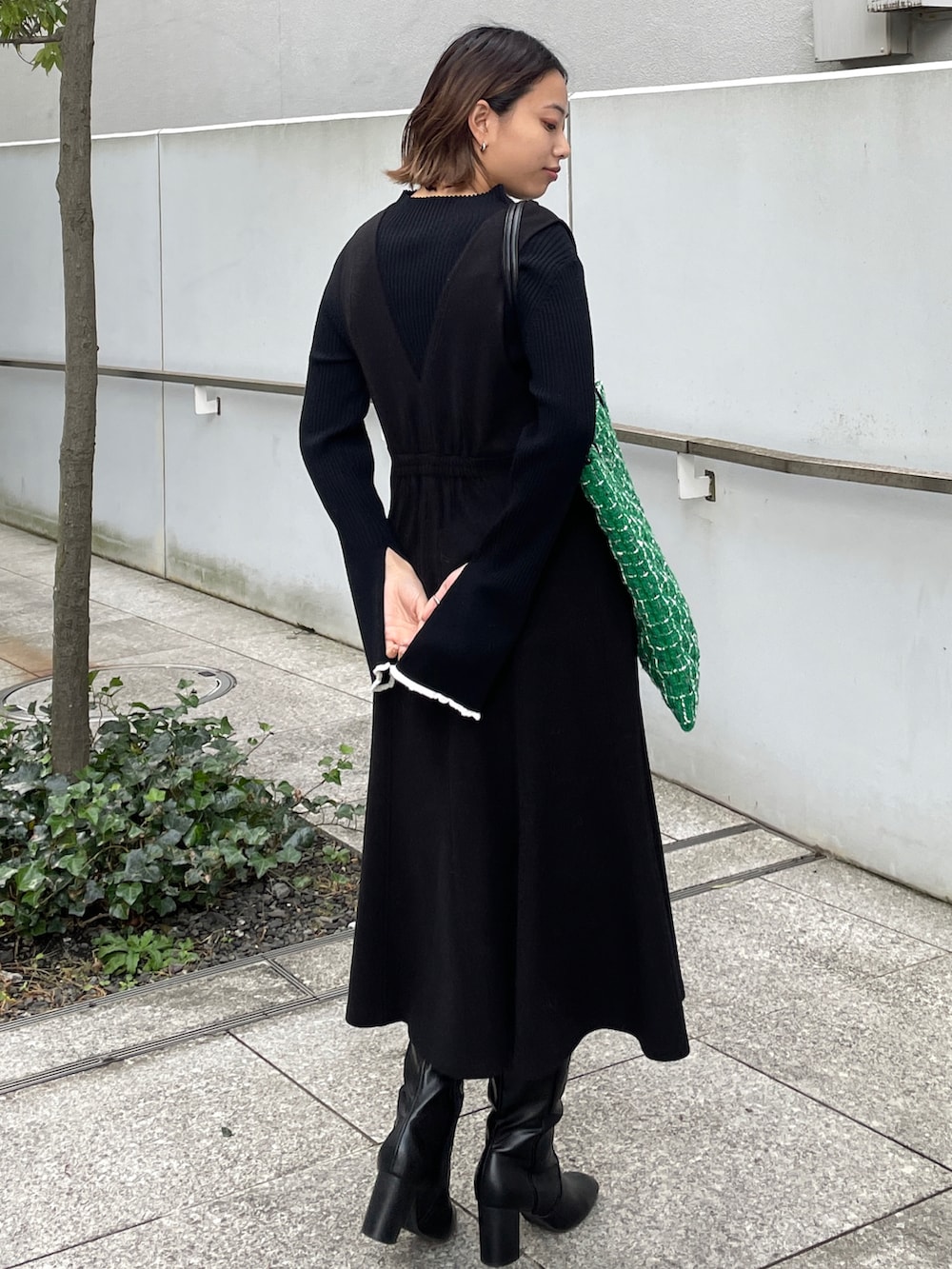 ブラック系のニット/セーター、ブラック系のスカート、グリーン系のトートバッグを着用したレディースの冬コーディネートの3枚目の写真