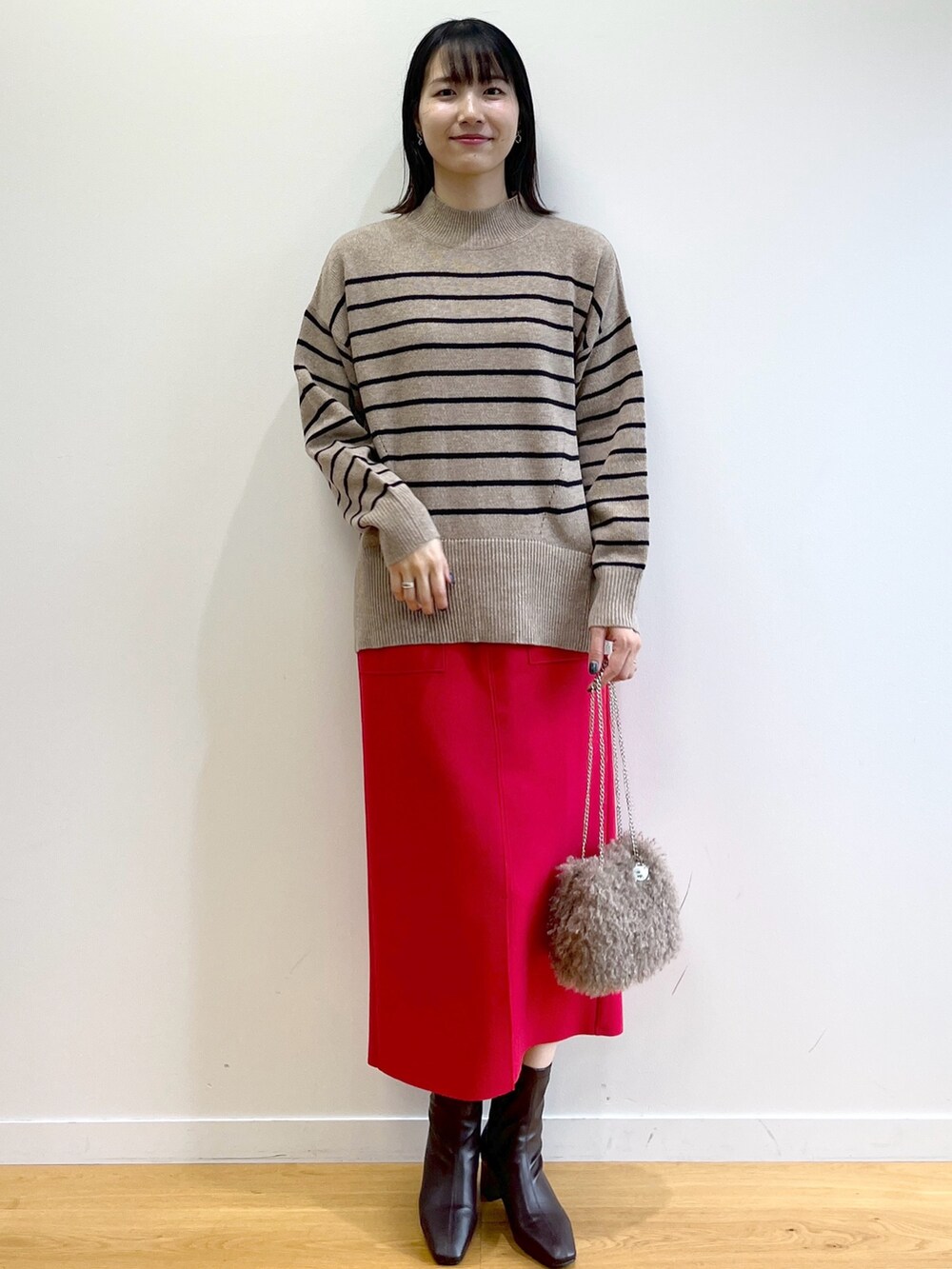 イエロー系のダウンジャケット/コート、ベージュ系のニット/セーター、レッド系のスカートを着用したレディースの秋コーディネートの8枚目の写真