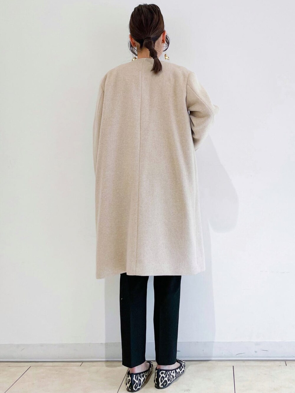 ベージュ系のノーカラーコート、ブラック系のトートバッグ、ブラック系のその他パンツを着用したレディースの秋コーディネートの3枚目の写真