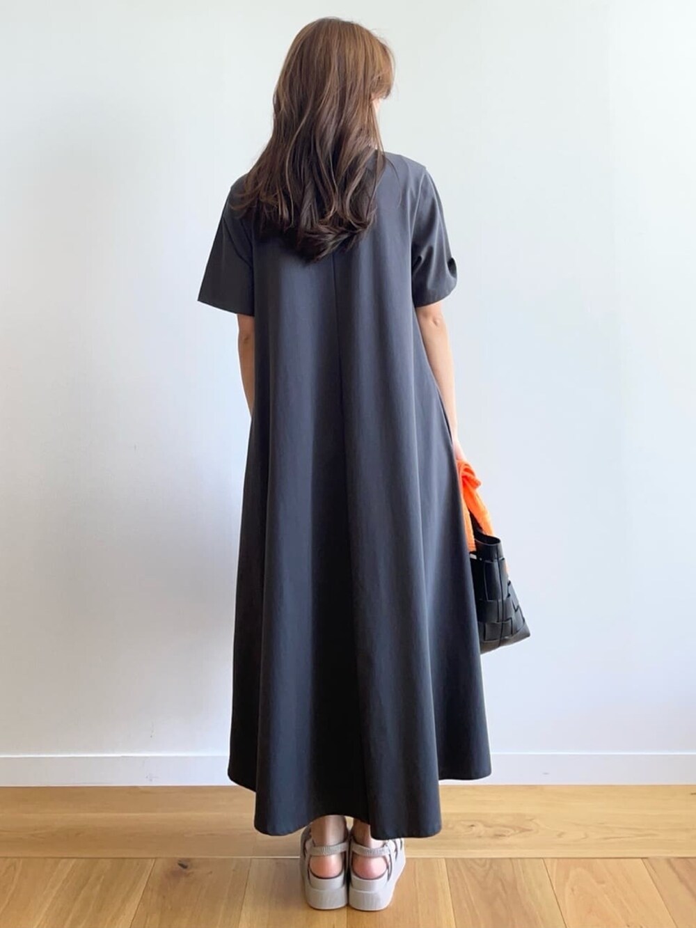グレー系のワンピース、グレー系のサンダル、ブラック系のトートバッグを着用したレディースの春コーディネートの3枚目の写真