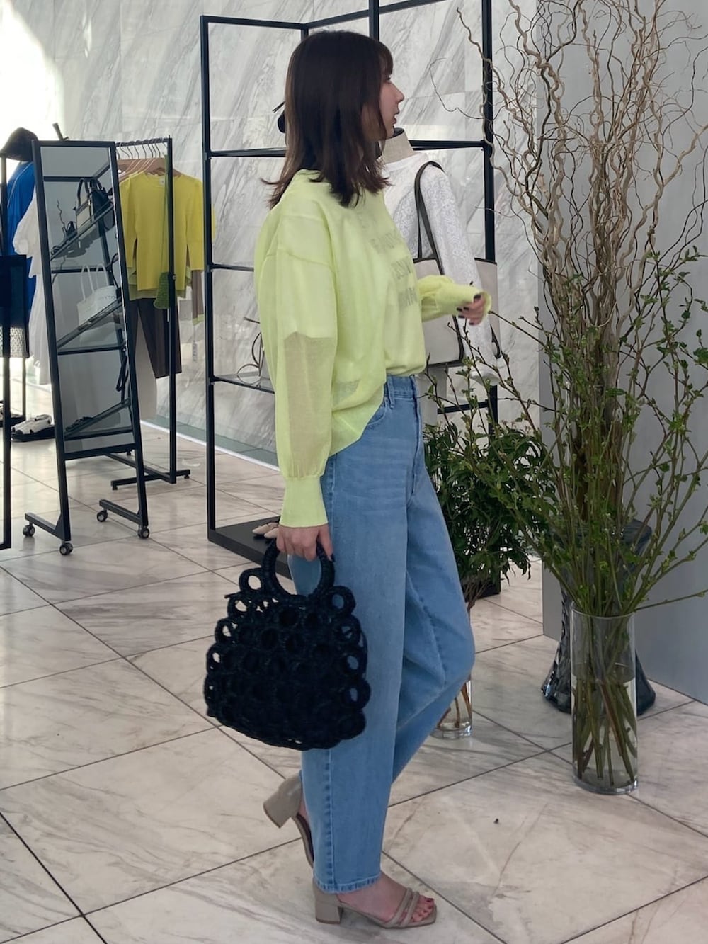 グリーン系のニット/セーター、ブルー系のデニムパンツ、ベージュ系のサンダルを着用したレディースの春コーディネートの3枚目の写真