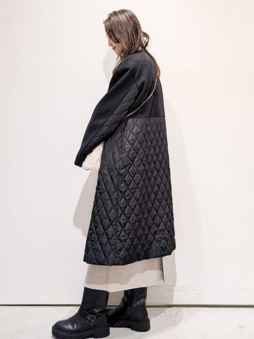 ホワイト系のショルダーバッグ、ブラック系のブーツ、ベージュ系のワンピースを着用したレディースの冬コーディネートの3枚目の写真