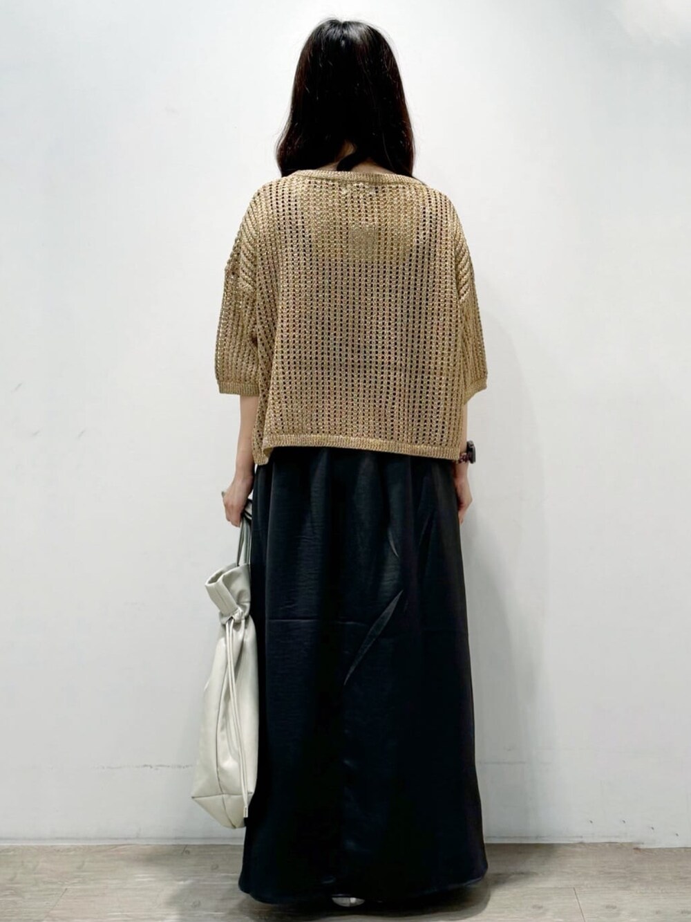 ゴールド系のニット/セーター、グレー系のトートバッグ、グレー系のスカートを着用したレディースの秋コーディネートの5枚目の写真