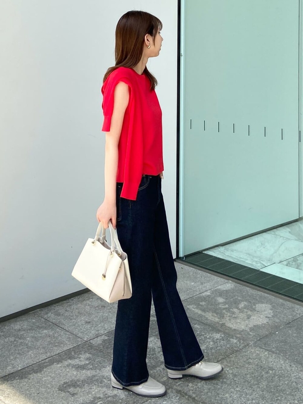 レッド系のカーディガン/ボレロ、レッド系のニット/セーター、ブルー系のデニムパンツを着用したレディースの夏コーディネートの3枚目の写真