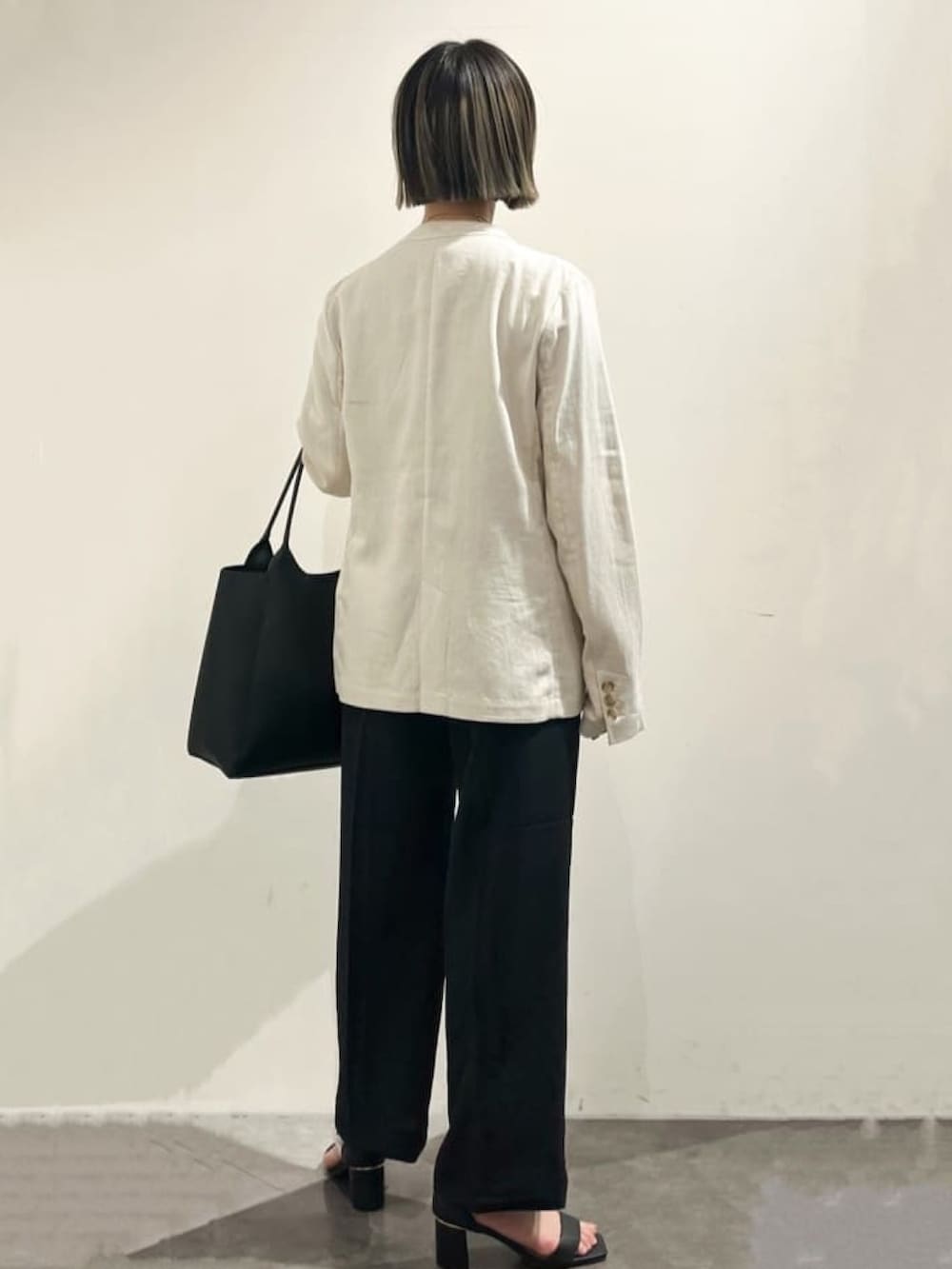 ベージュ系のノーカラージャケット、ブラウン系のニット/セーター、ブラック系のトートバッグを着用したレディースの春コーディネートの2枚目の写真