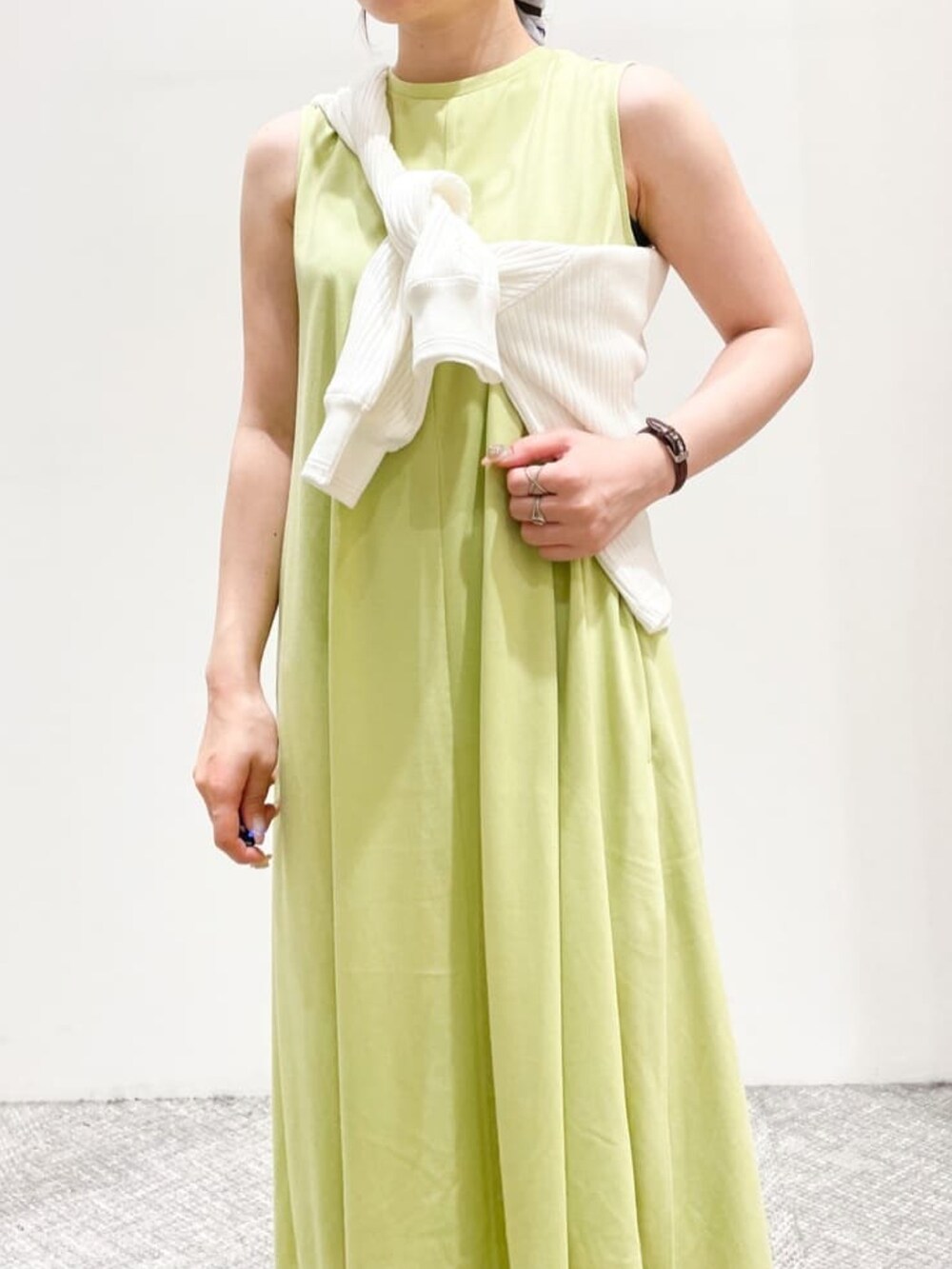 グリーン系のワンピース、ホワイト系のカーディガン/ボレロ、ブラック系のサンダルを着用したレディースの夏コーディネートの3枚目の写真