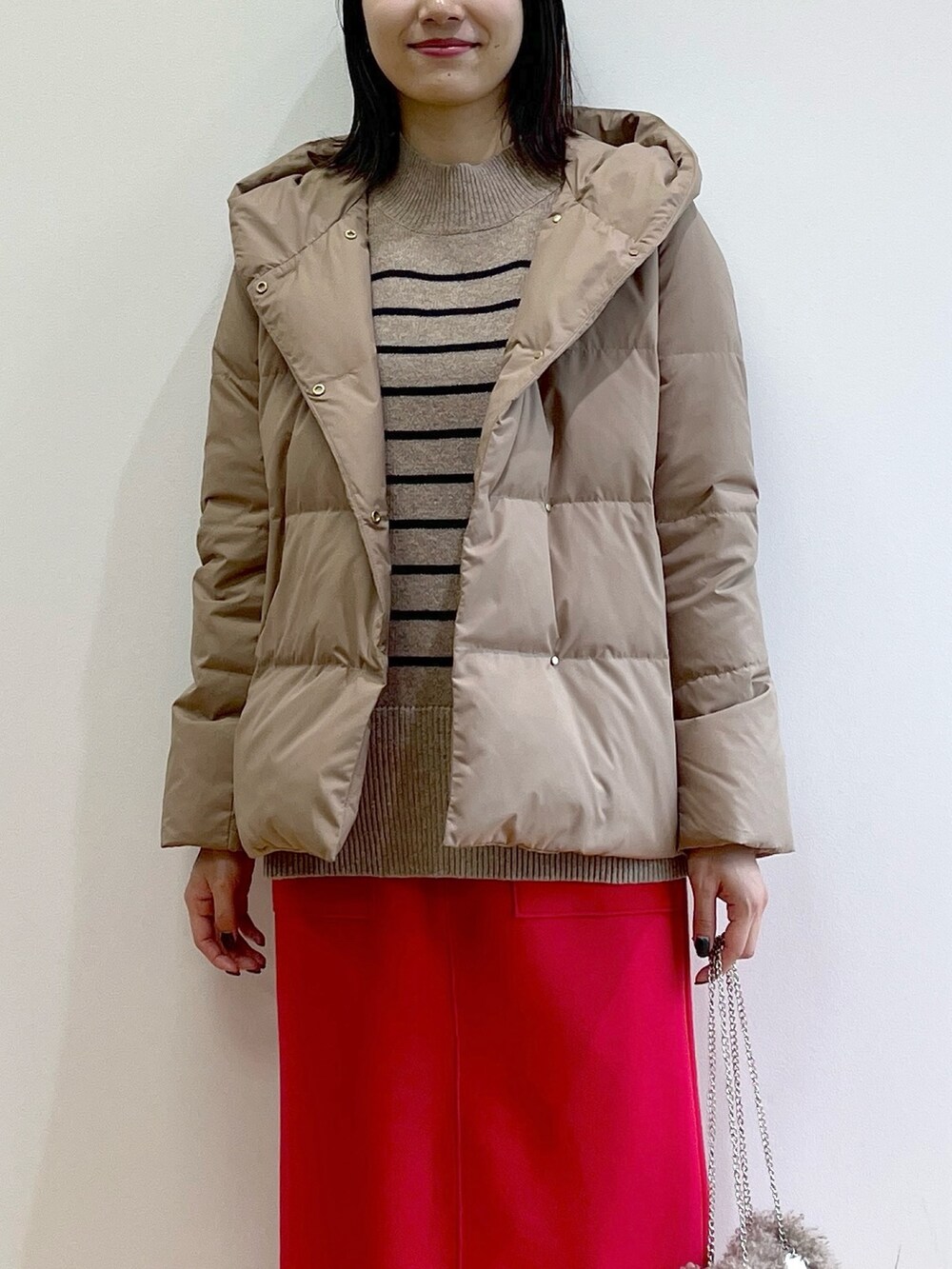 イエロー系のダウンジャケット/コート、ベージュ系のニット/セーター、レッド系のスカートを着用したレディースの秋コーディネートの6枚目の写真