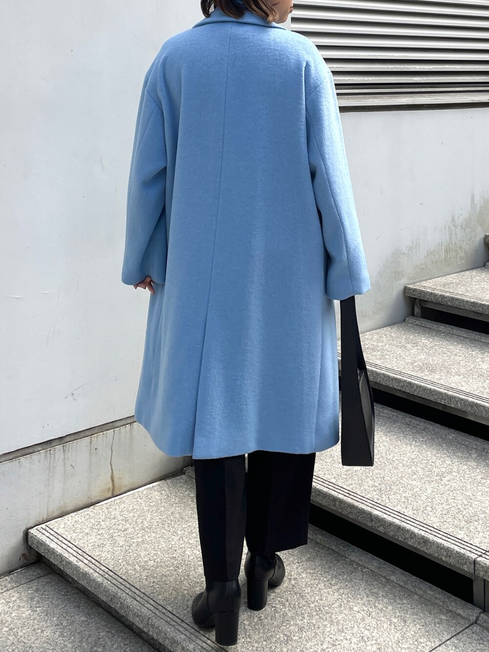 ブルー系のチェスターコート、ホワイト系のニット/セーター、ブラック系のその他パンツを着用したレディースの冬コーディネートの3枚目の写真