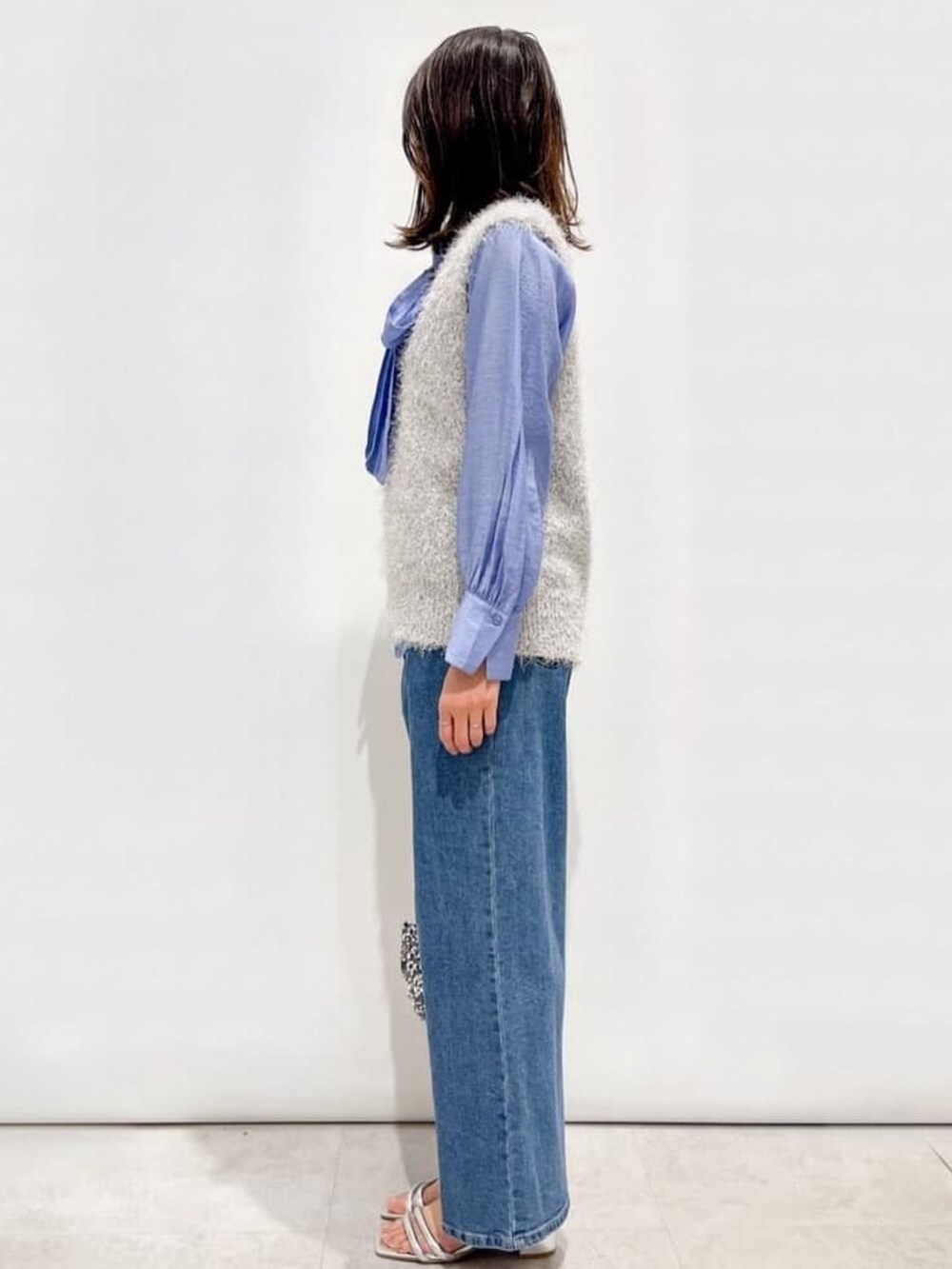 グレー系のベスト、ブルー系のシャツ/ブラウス、ブルー系のデニムパンツを着用したレディースの春コーディネートの2枚目の写真