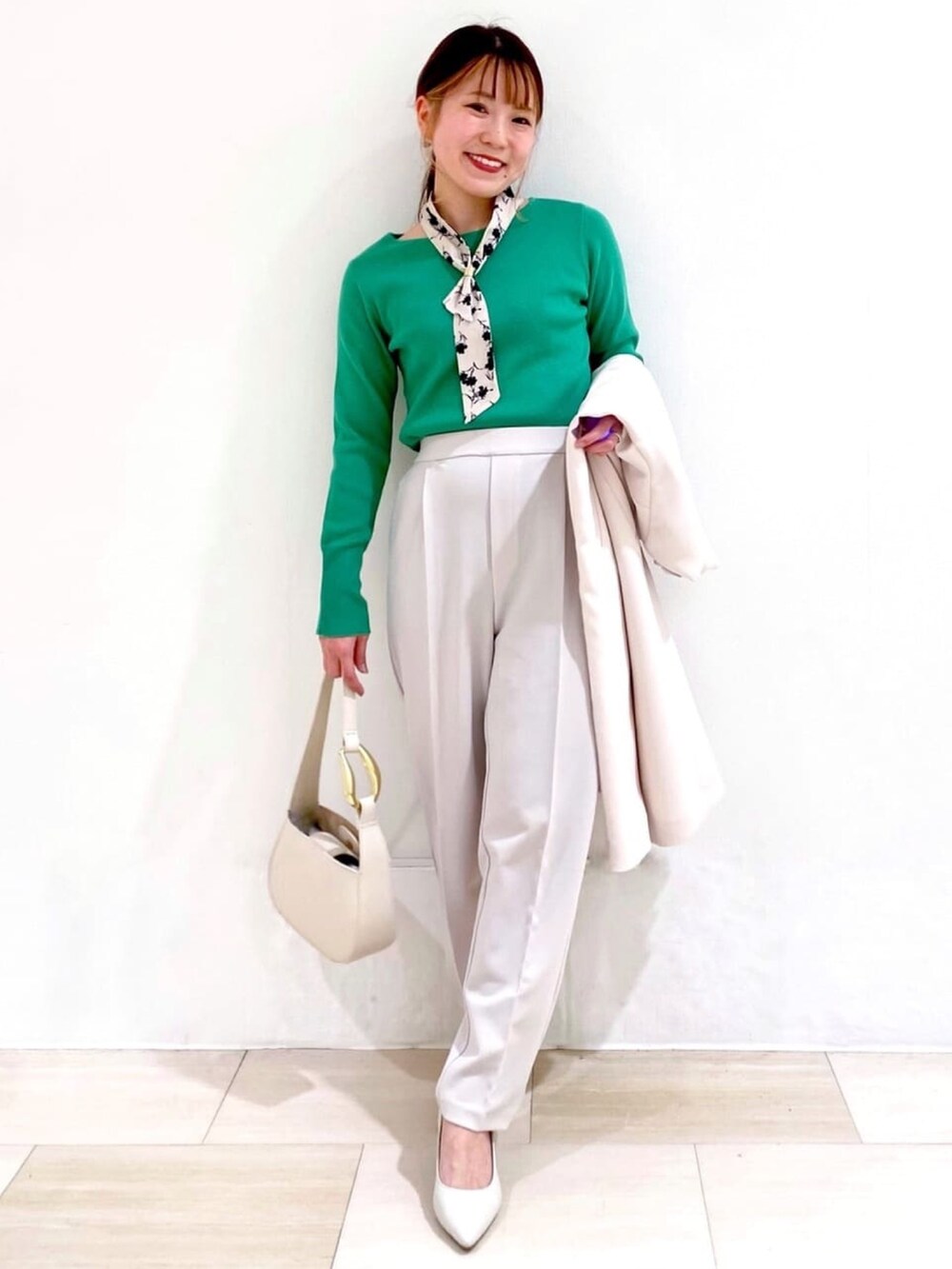ホワイト系のノーカラーコート、グリーン系のニット/セーター、ホワイト系のパンプスを着用したレディースの冬コーディネートの4枚目の写真