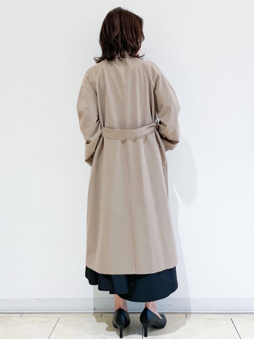 ベージュ系のトレンチコート、グリーン系のニット/セーター、ブラック系のトートバッグを着用したレディースの秋コーディネートの3枚目の写真