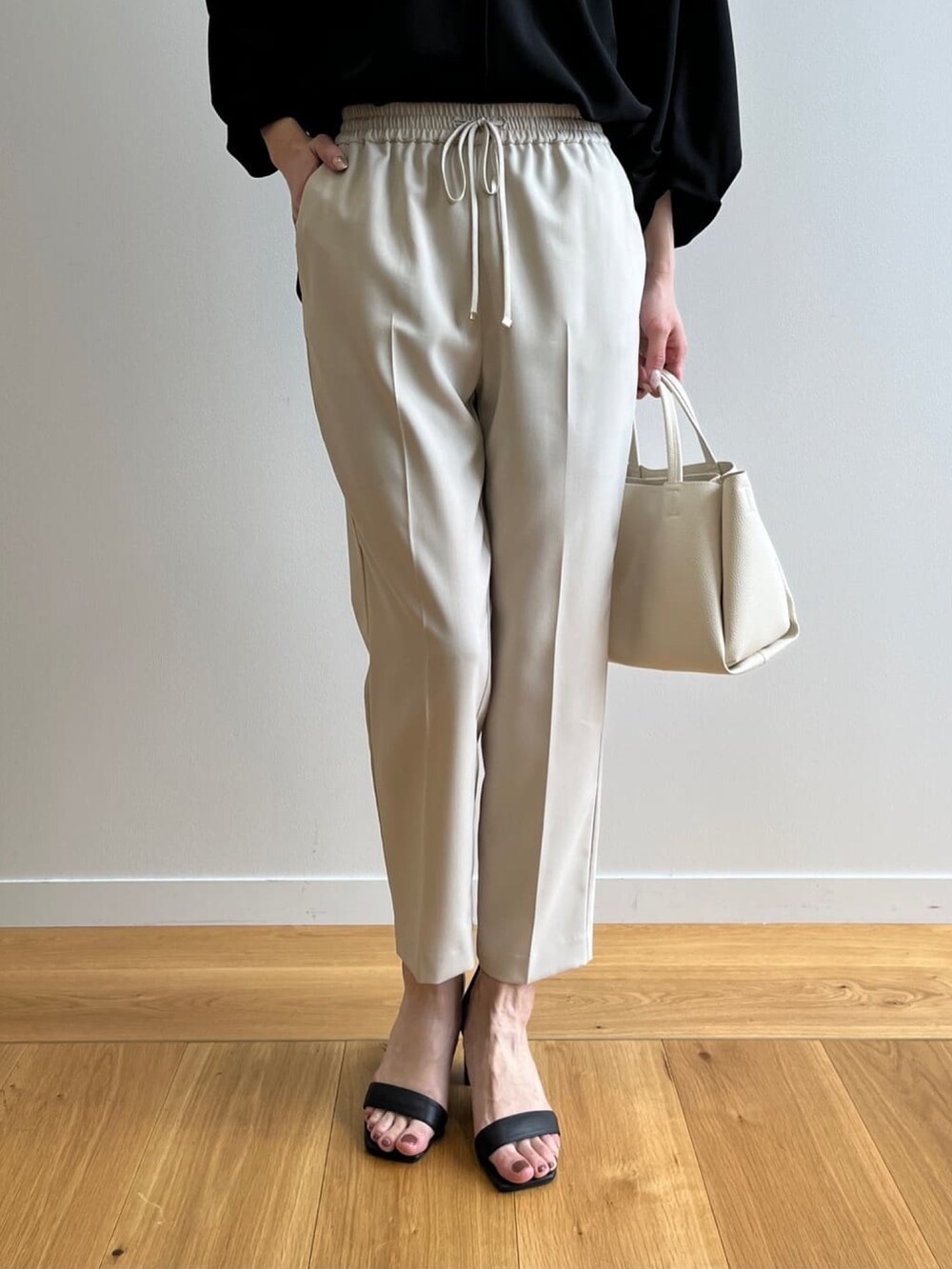 ブラック系のTシャツ/カットソー、ベージュ系のその他パンツ、ブラック系のサンダルを着用したレディースの春コーディネートの6枚目の写真