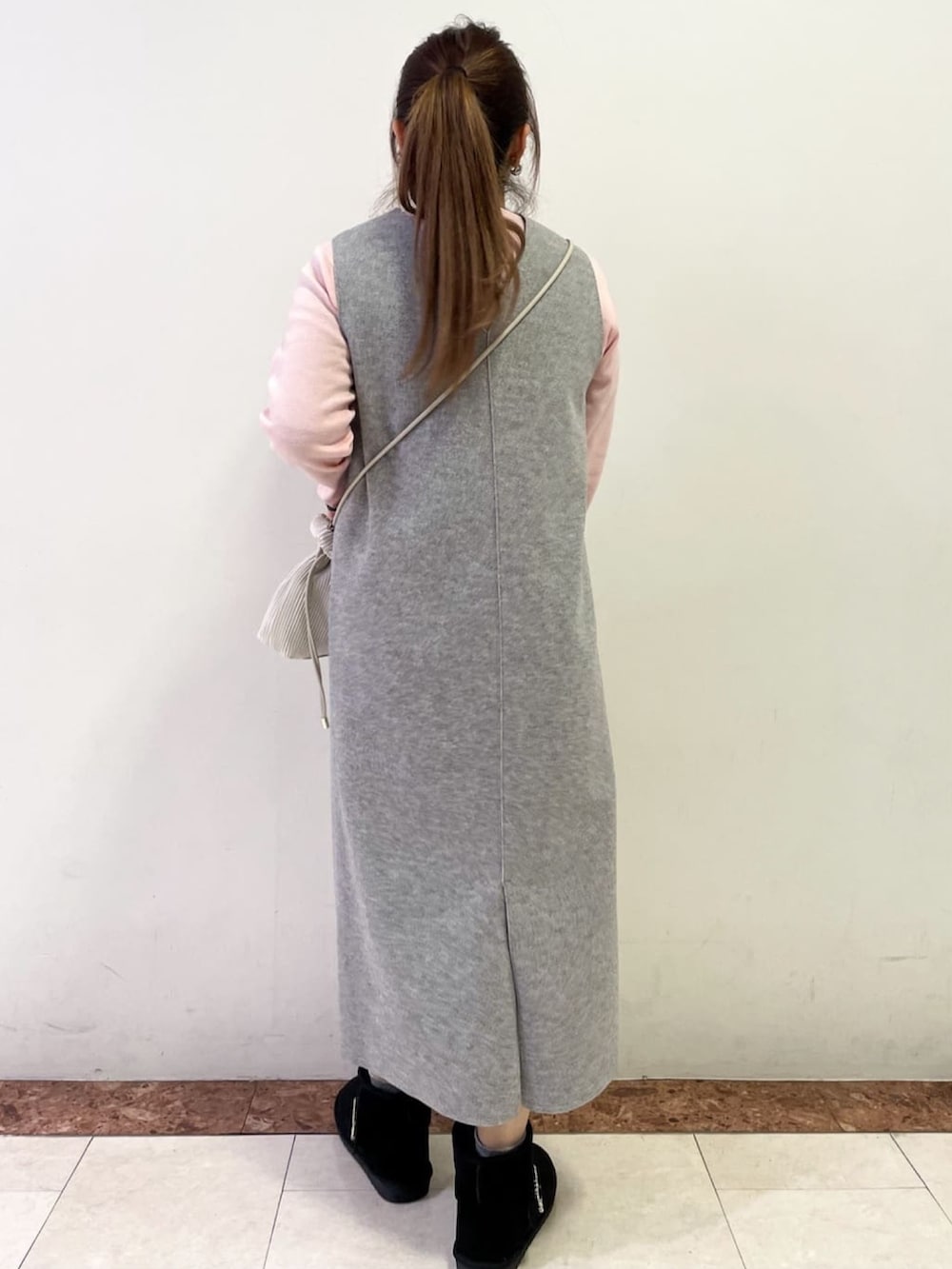 ベージュ系のショルダーバッグ、ブラック系のブーツ、グレー系のスカートを着用したレディースの冬コーディネートの3枚目の写真