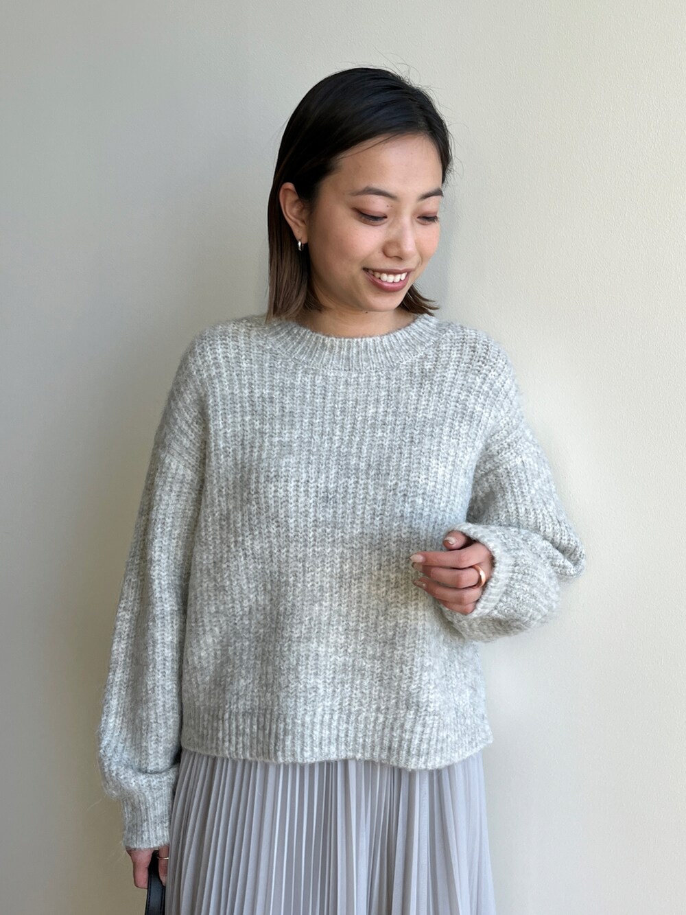 グレー系のニット/セーター、グレー系のスカート、ブラック系のブーツを着用したレディースの冬コーディネートの4枚目の写真