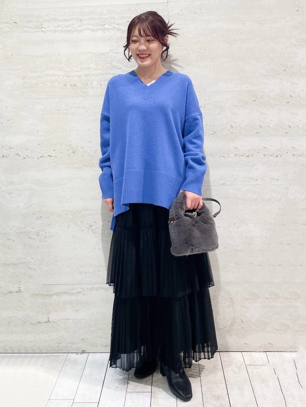 ブラック系のチェスターコート、レッド系のニット/セーター、グレー系のスカートを着用したレディースの秋コーディネートの2枚目の写真