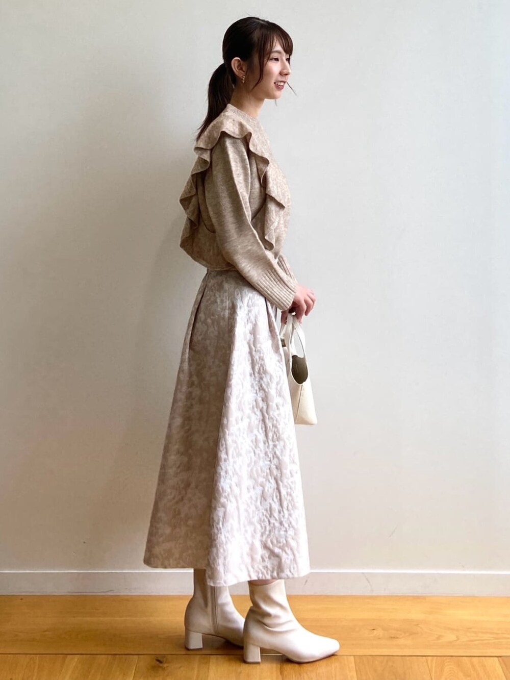 ベージュ系のニット/セーター、ホワイト系のトートバッグ、ベージュ系のスカートを着用したレディースの秋コーディネートの2枚目の写真
